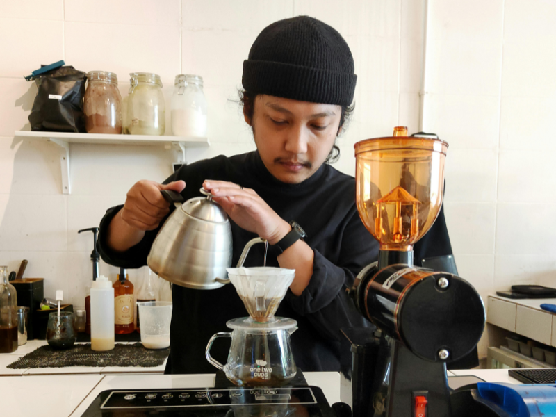 Barista servindo café especial de fermentação anaeróbica em cafeteria, conectando inovação com consumo consciente.