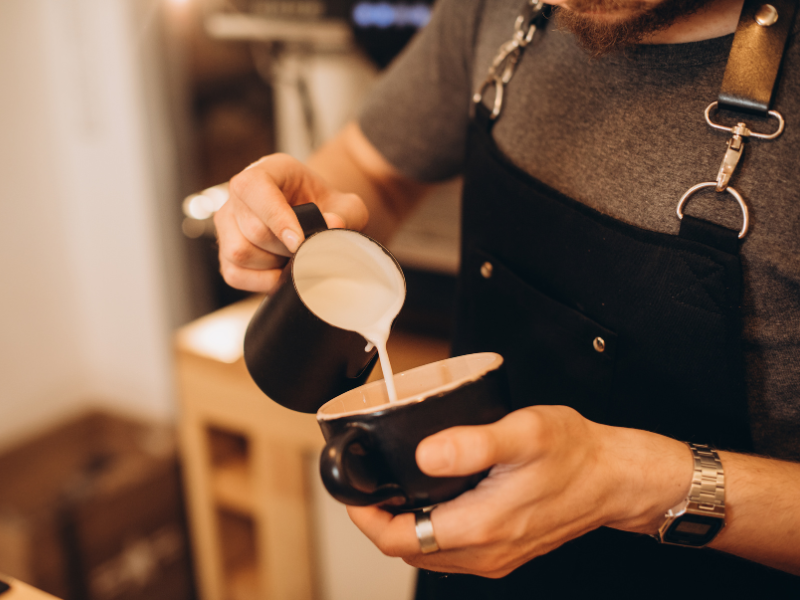 Barista preparando café filtrado em cafeteria contemporânea, símbolo da história do café atual.